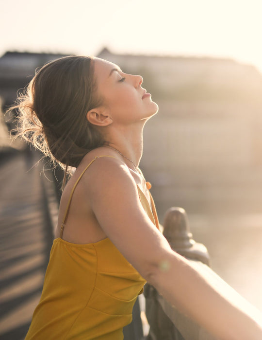 woman standing outside at sunrise facing the sun with her face uplifted and a sense of freedom and confidence at knowing how to balance her hormones successfully <a href=